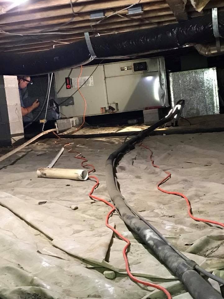 HVAC technician servicing ductwork in a crawlspace near Erwin, NC